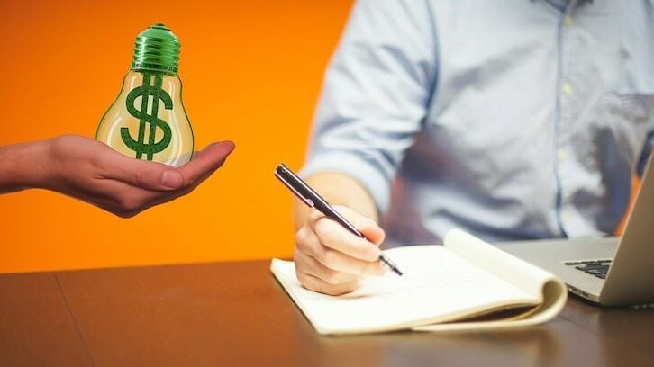 una persona escribiendo notas sobre cómo ganar dinero blogueando en línea